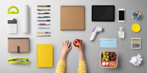 A desk organized with various professional and personal items including an apple inside of a woman's hand