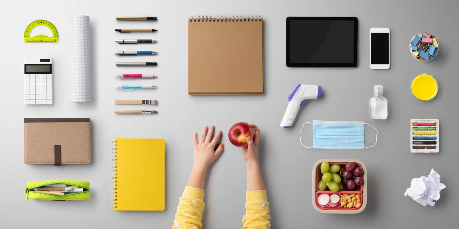 A desk organized with various professional and personal items including an apple inside of a woman's hand